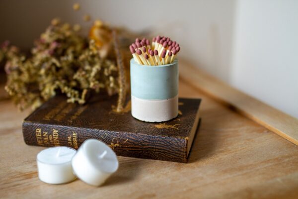 Sage green striker pot displayed on a book